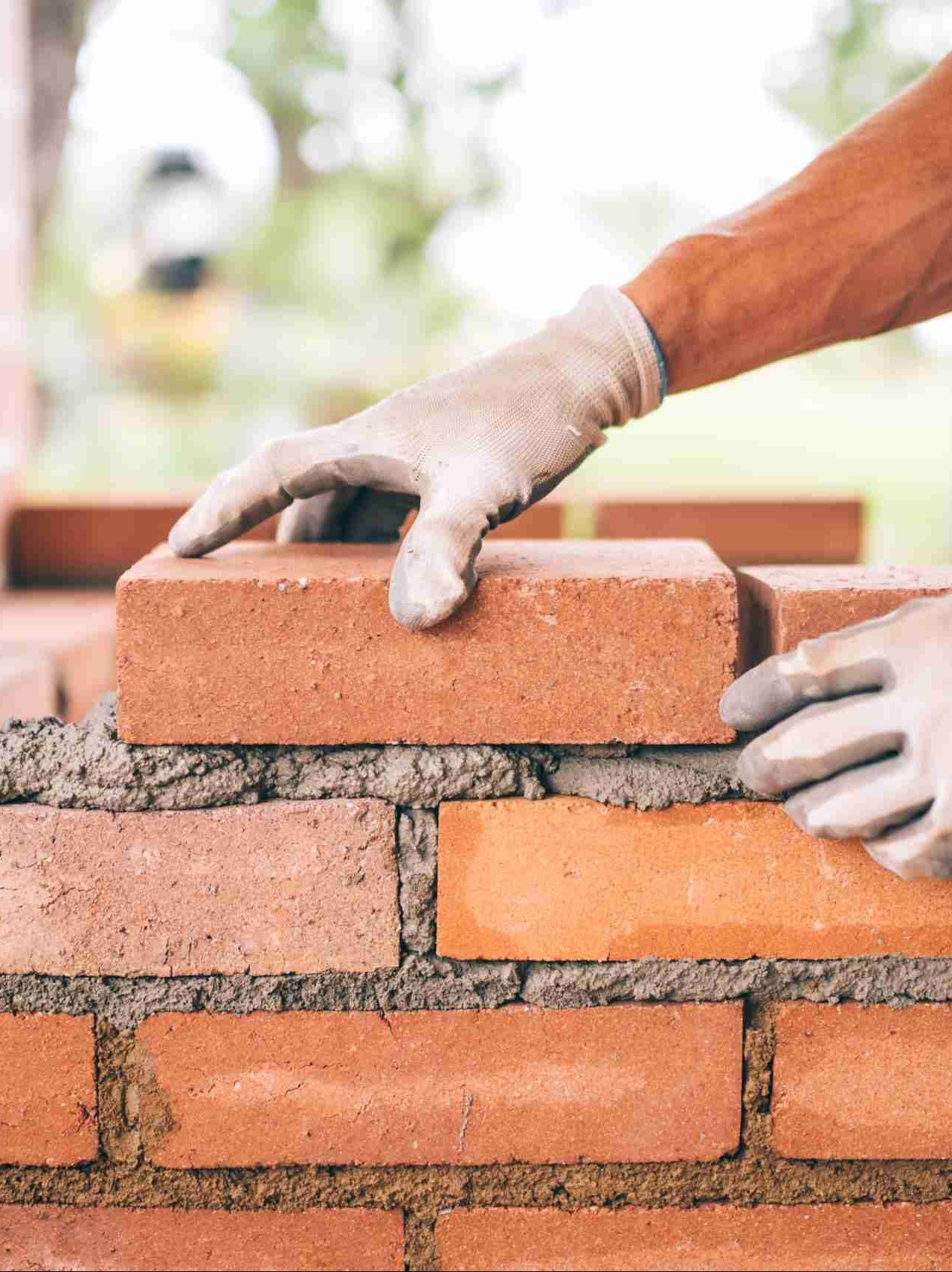 professional construction worker laying bricks and building barbecue in industrial site. Detail of hand adjusting bricks